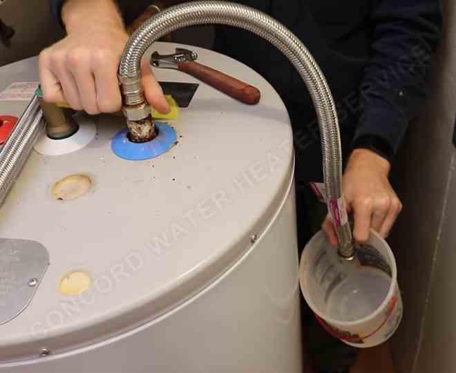 Concord plumber draining water heater during emergency leak repair