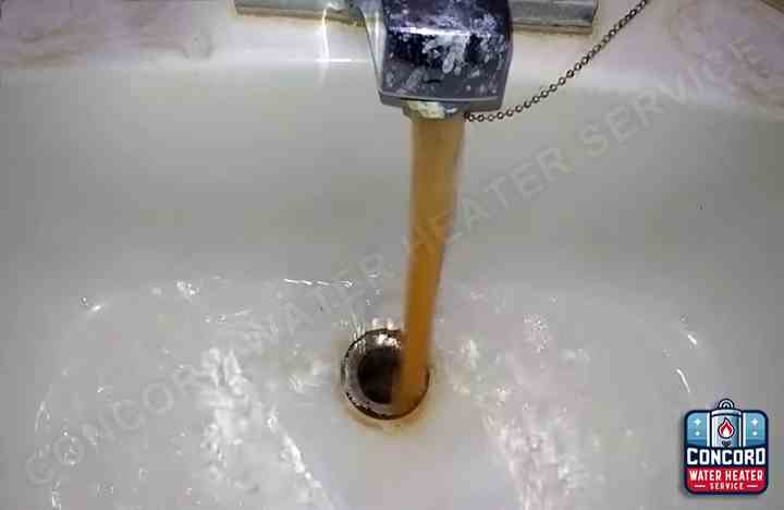 Bathroom sink with orange-brown rusty water flowing from the faucet in Concord, CA, showing severe water discoloration from water heater corrosion.