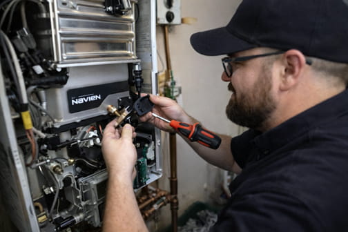 Technician repairing Navien tankless water heater system in College Park neighborhood in Pleasant Hill