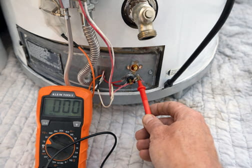 Water heater technician using multimeter to diagnose electrical issues during Pleasant Hill repair service