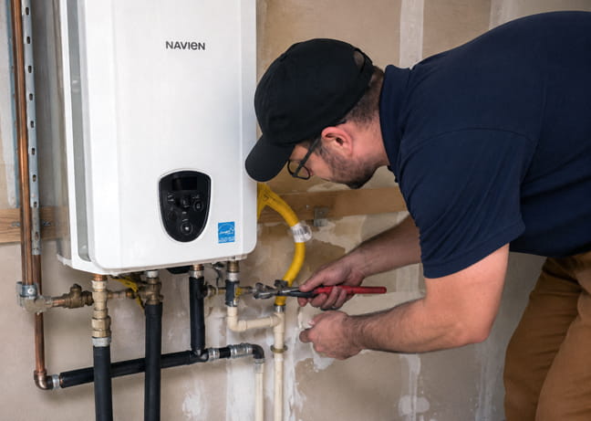 Technician servicing a Navien tankless water heater system in San Ramon